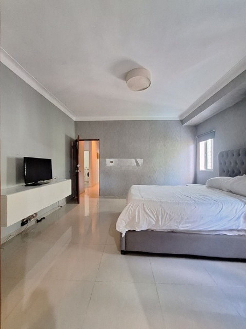 Master bedroom with upholstered bed and TV